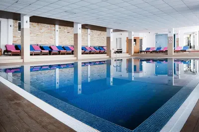 a swimming pool with blue and red chairs in a building at Milmari boutique S3 lux in Kopaonik