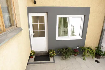 a white door and windows on a building with potted plants at Radman's house in Niš