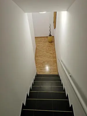 a hallway with a staircase with black tiles at Radman's house in Niš