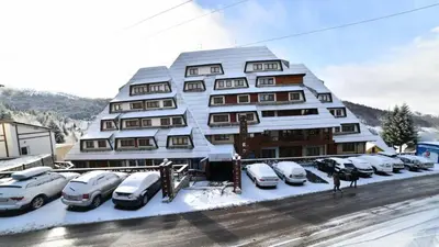 a large building with cars parked in a parking lot at Apartman Planinski raj in Kopaonik