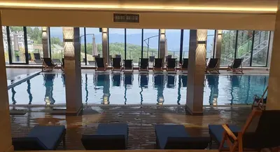 a swimming pool with chairs in a building at K19 Milmari Resort & Spa in Kopaonik