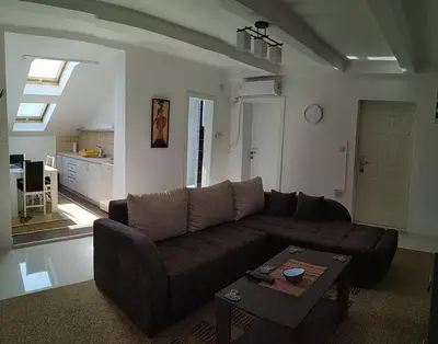 a living room with a brown couch and a table at BC Apartments in Niš