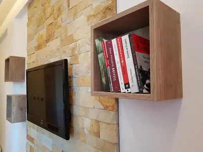 a tv on a brick wall with a book shelf at Apartment S&A Milmari Resort S43 in Kopaonik