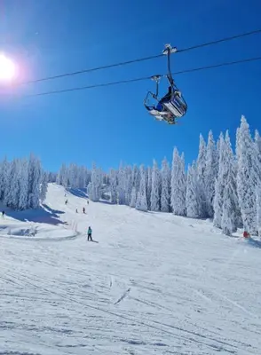 a person riding a ski lift on a snow covered slope at Apartment S&A Milmari Resort S43 in Kopaonik