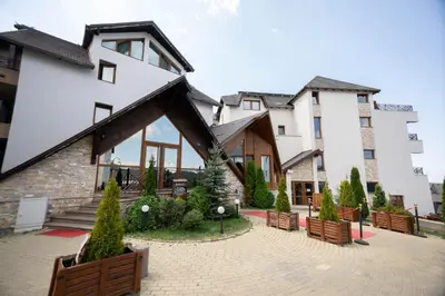 a large white building with trees in a courtyard at Milmari Resort & Spa Suites in Kopaonik