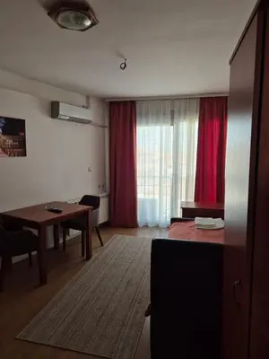 a living room with a table and a red curtain at Sobe Rooms Aleksandar in Niš
