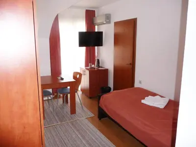 a bedroom with a bed and a desk and a mirror at Sobe Rooms Aleksandar in Niš