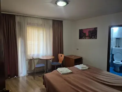 a hotel room with a bed and a table and chairs at Sobe Rooms Aleksandar in Niš