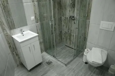 a bathroom with a shower and a toilet and a sink at Fine Suites in Niš