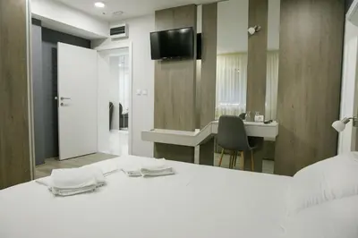a bedroom with a white bed and a mirror at Fine Suites in Niš