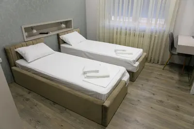 two twin beds in a room with a desk at Fine Suites in Niš