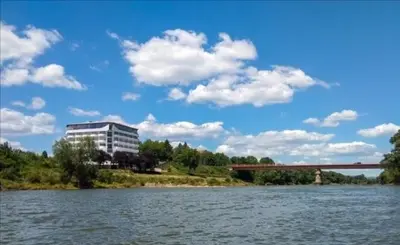 a building on the bank of a river with a bridge at Plaža in Varvarin