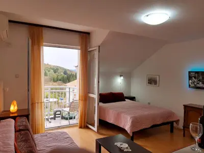 a bedroom with a bed and a sliding glass door at Sky Apartman in Soko Banja