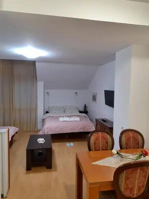 a bedroom with a bed and a table and chairs at Sky Apartman in Soko Banja