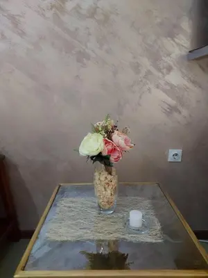 a vase of flowers on a table with a candle at Apartmani Neca in Vrnjačka Banja