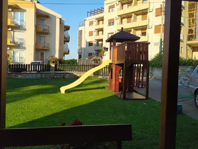 a playground with a yellow slide in a yard at Apartmani Neca in Vrnjačka Banja