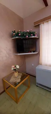 a living room with a table and a shelf with flowers at Apartmani Neca in Vrnjačka Banja