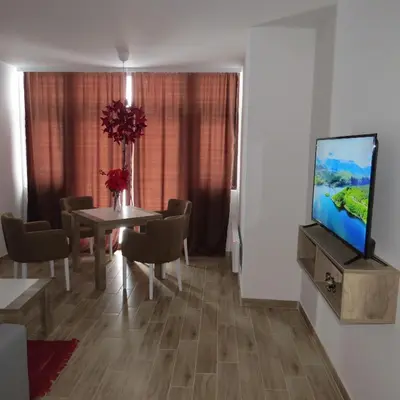 a dining room with a table and a tv on a wall at Dvori E11 Hilltop in Kopaonik