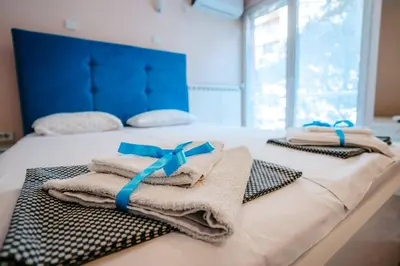 two towels on a bed with blue bows on them at Turist Apartment in Niš