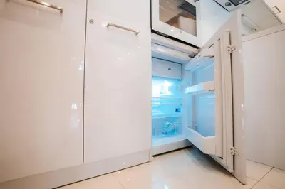 a walk in closet with white cabinets and a refrigerator at Turist Apartment in Niš