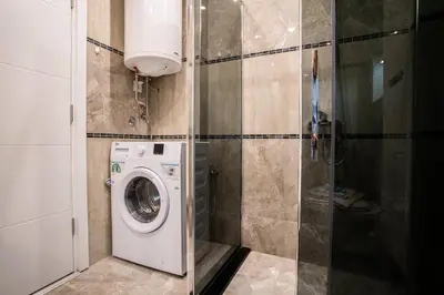 a bathroom with a washing machine and a shower at Turist Apartment in Niš