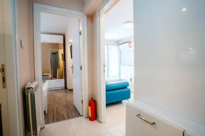 a room with a hallway with a blue couch and a mirror at Turist Apartment in Niš