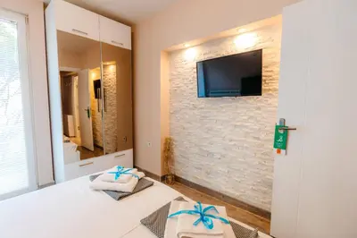 a bedroom with a tv on a brick wall at Turist Apartment in Niš