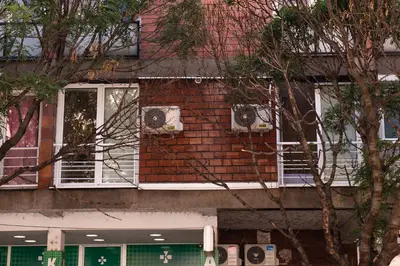 a red brick building with two windows and two fans at Turist Apartment in Niš