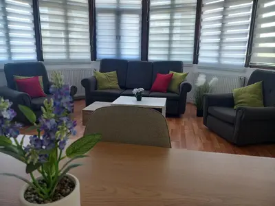 a living room with couches and a table and flowers at Apartmani Ćosić in Kuršumlija