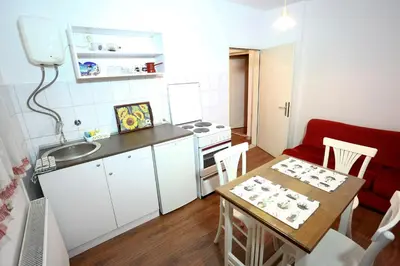 a small kitchen with a table and a red couch at Apartman Carpe Diem in Zaječar