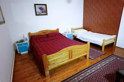 a bedroom with a wooden bed and two small beds at Apartman Carpe Diem in Zaječar