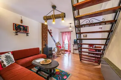 a living room with a couch and a spiral staircase at Planinske Vile M&S in Kopaonik