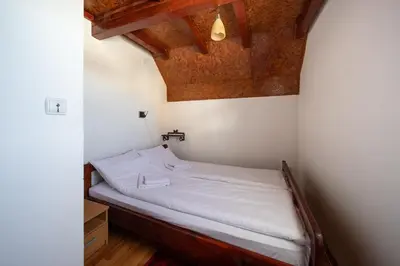 a small bed in a room with a wooden ceiling at Planinske Vile M&S in Kopaonik