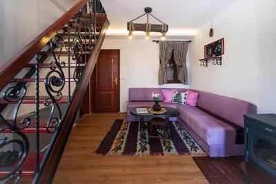 a living room with a purple couch and a staircase at Planinske Vile M&S in Kopaonik