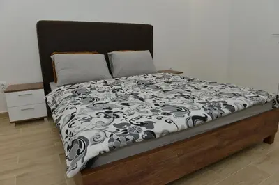 a bed with a black and white comforter at Apartman Jankulovski in Kraljevo