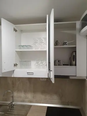 a kitchen with white cabinets with dishes in it at Apartman Jankulovski in Kraljevo