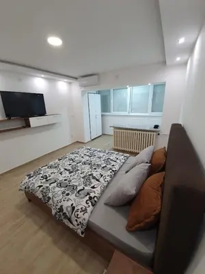 a bedroom with a bed with a black and white blanket at Apartman Jankulovski in Kraljevo