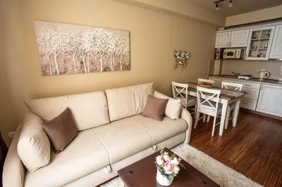 a living room with a white couch and a kitchen at Planinska bajka - Kraljevi čardaci in Kopaonik