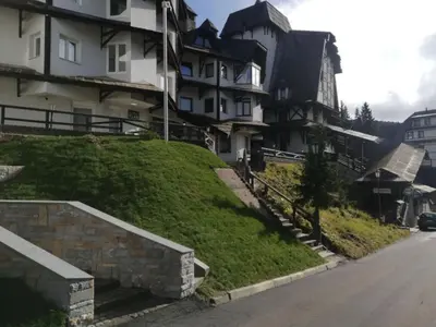 a house on a grassy hill next to a street at Vila Plan - Centar Kopaonik in Kopaonik