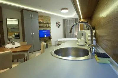 a kitchen with a sink and a living room at Apartman BIG Milmari S19 in Kopaonik