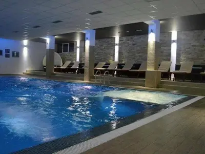 a large swimming pool in a building with chairs at Premier 29 Milmari Resort Wellness&Spa in Kopaonik