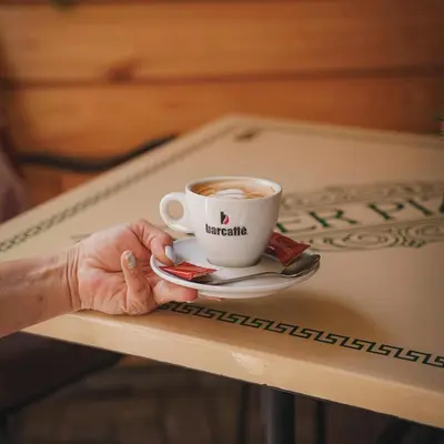 a person holding a cup of coffee on a table at Apartman Downtown in Vrnjačka Banja
