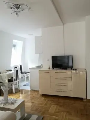 a white living room with a television on a dresser at Apartman Downtown in Vrnjačka Banja