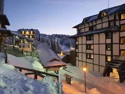 a building covered in snow next to a street light at Vila Plan centar Kopaonik in Kopaonik