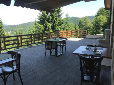 a patio with tables and chairs and a fence at Vila Lucky Kop & Restoran in Kopaonik