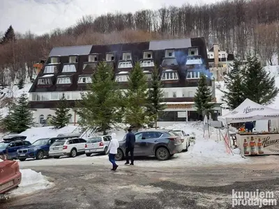 two people walking in front of a large building at Vila Košuta - Kopaonik, Brzeće 30m from gondola in Brzeće