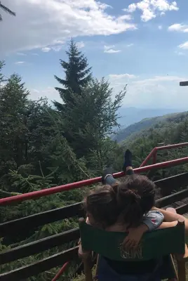 a woman and child sitting on a bench looking at the mountains at Weekendica in Kopaonik