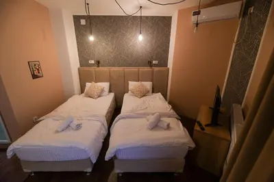 two beds in a room with white sheets at Corner Apartmani in Leskovac