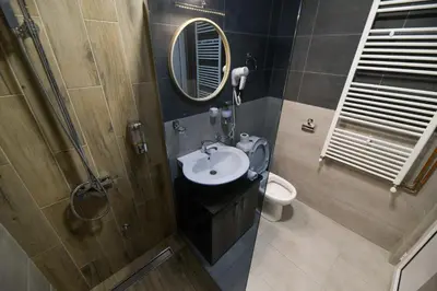 a bathroom with a sink and a mirror and a toilet at Corner Apartmani in Leskovac