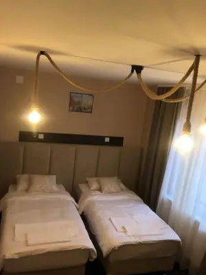 two beds in a hotel room with lights on at Corner Apartmani in Leskovac